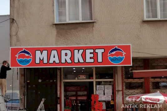 Market vinil baskılı cephe tabelası kırmızı zemin beyaz yazı yunuslu logo dış mekan uygulaması